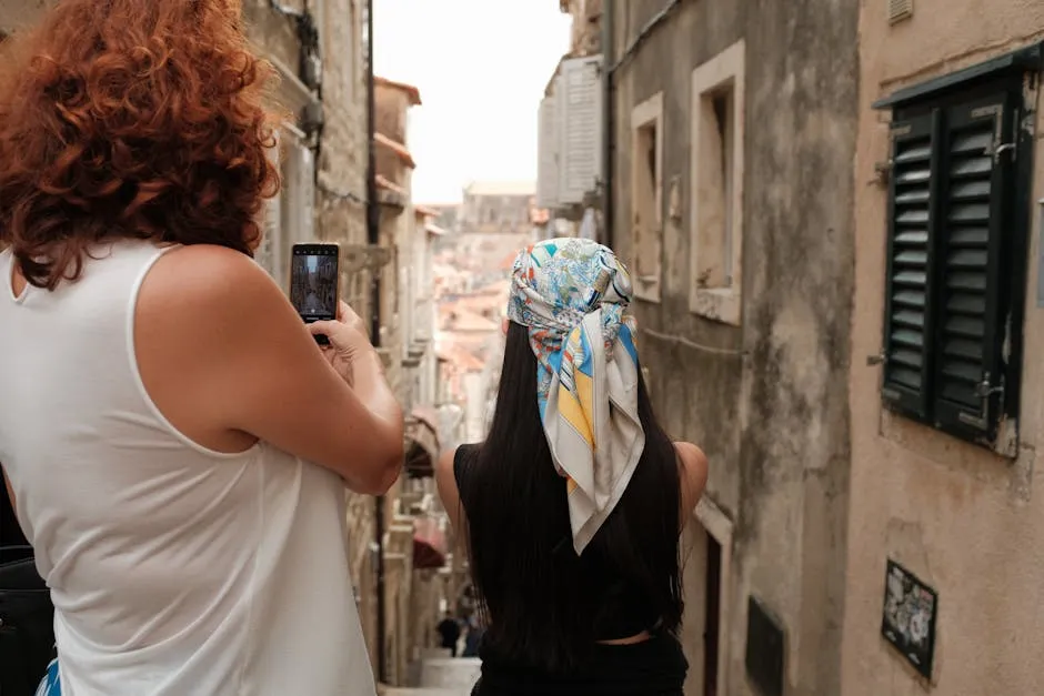 Two women with smartphones exploring narrow alley in Dubrovnik old town Croatia