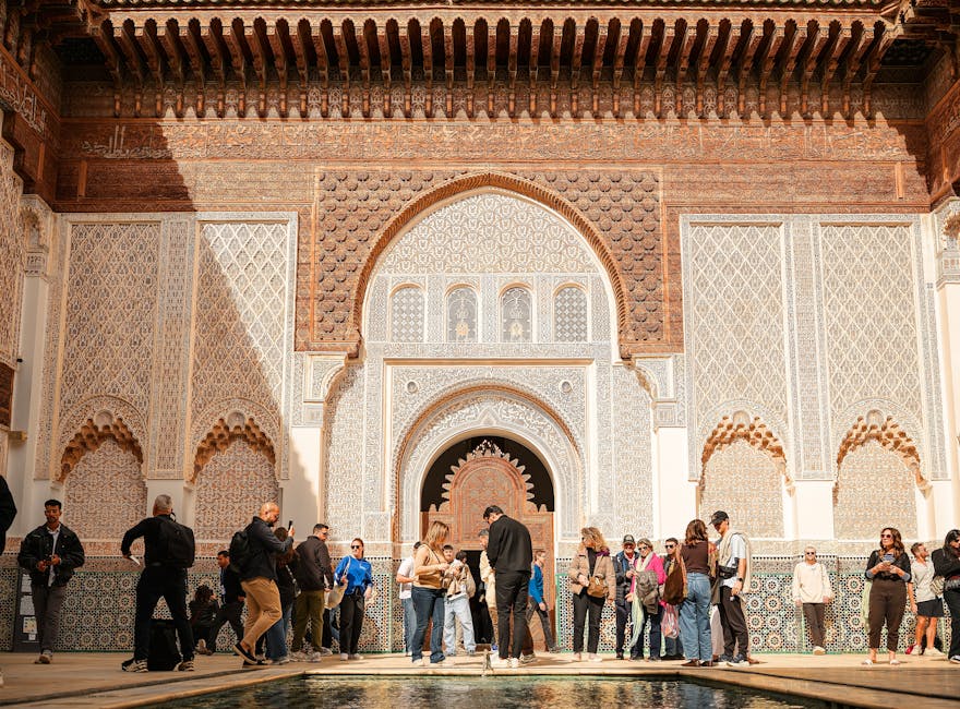 Tourists exploring Ben Youssef Madrasa in Marrakech using their phones for navigation